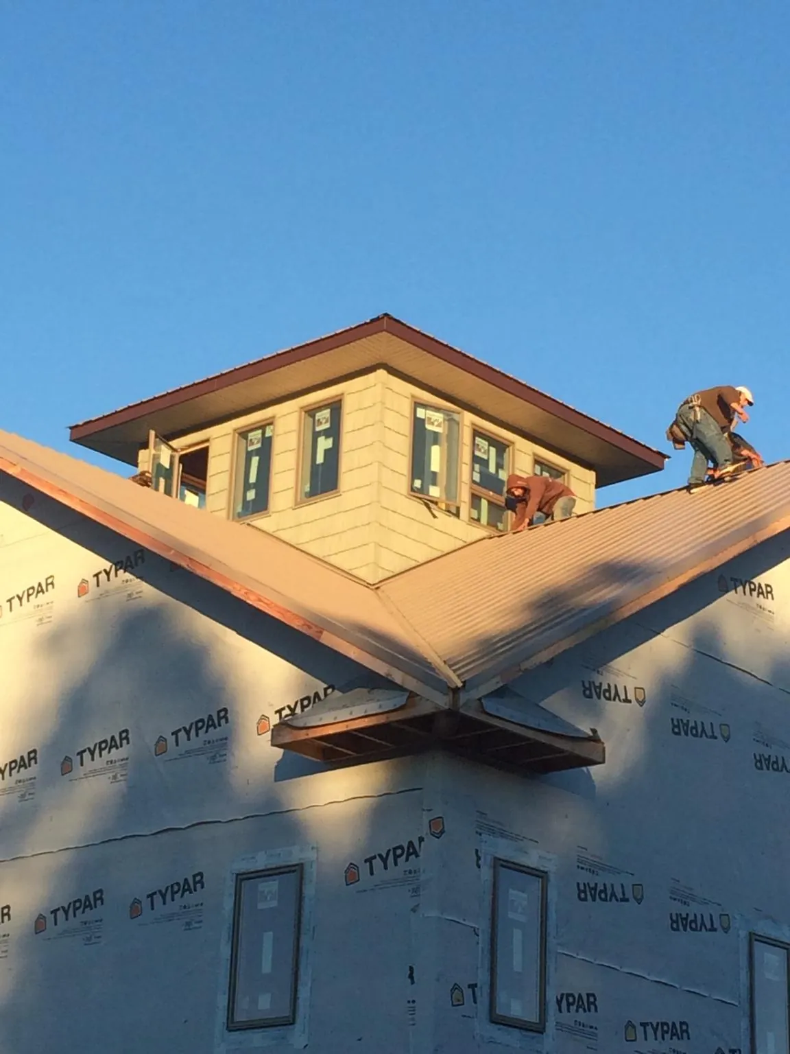 Roofers working around a rooftop cupola on a new metal roof at sunset — Roof Waterproofing in San Jose by Roofing Brothers